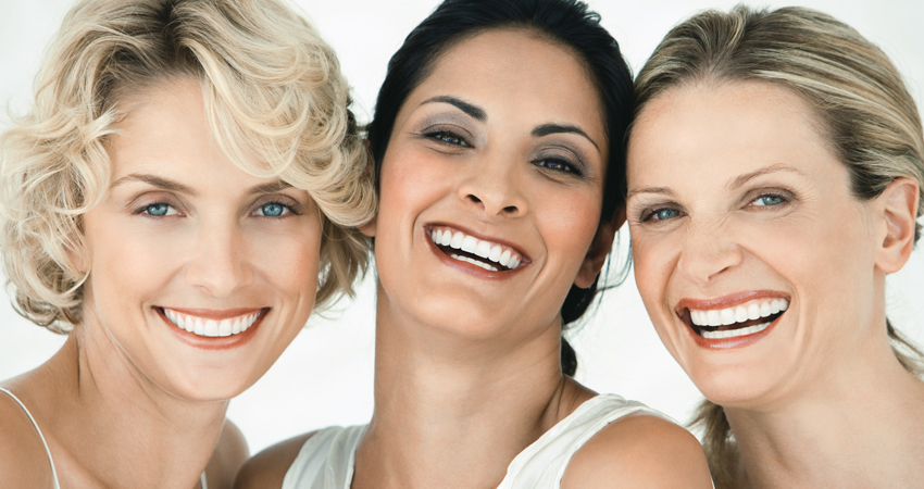 Three female friends with dental bonding share smiles