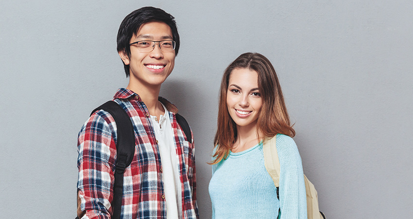 Two teenagers with backpacks smile